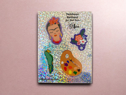 stickers frida Kahlo finition pailletée holographique. cette planche de stickerst comporte une petite tete Frida, un bouquet de fleurs, une palette d&#39;artiste, un perroquet.format A6.