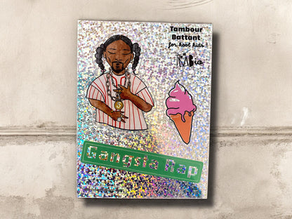 planche de papier holographique contenant 3 stickers : en haut à gauche, un dessin inspiré de snoop doggy dog, au milieu et à droite une glace à l’italienne rose, et en bas une bande verte avec le mot Gangsta rap en lettres pailletées.